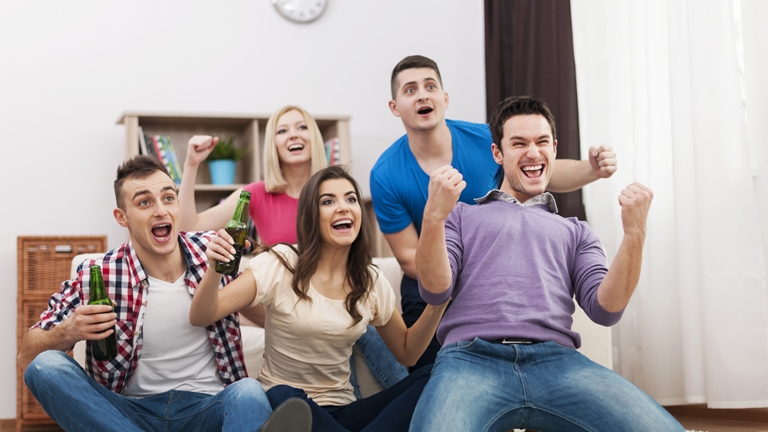 group of fans cheering while watching tv
