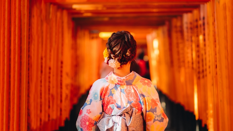 woman in kimono walking through japanese torii