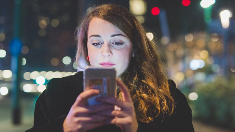 a woman holding a phone at night