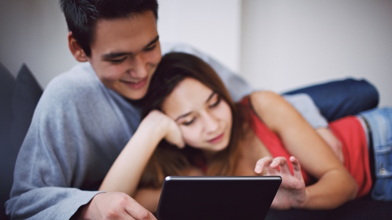 couple using phone on their bed