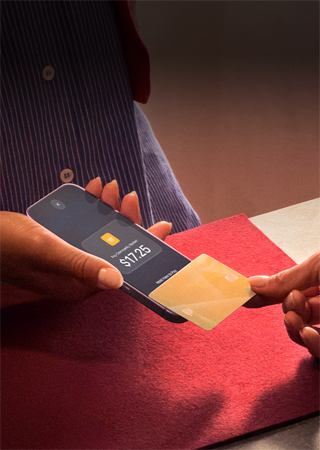 A hand taps a credit card to an iPhone to complete a payment